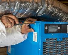 crew member installing a dehumidifier in a basement