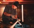 crew member in crawl space installing sump pump