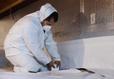 The production crew is installing a vapor barrier in crawl space.