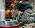 crew members installing interior drains and a sump pump in a basement