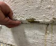 Close up of hand checking shifted basement wall.