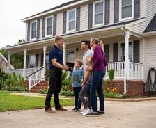 CFI standing outside of home with a family.