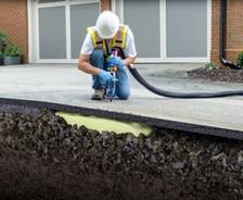 man installing polyurethane foam under concrete driveway
