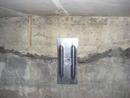Metal plate with a keyhole mounted on a concrete wall with visible cracks and rough texture.