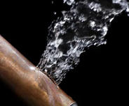 Water spraying out of a cracked copper pipe against a black background highlights the unseen battles beneath our homes, where shifting foundation soils can wreak havoc.