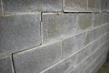 Close-up of a gray concrete block wall with visible cracks and signs of wear.