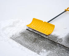 Shovel on uneven driveway covered in snow.