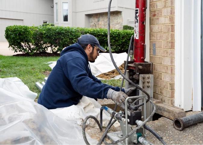 Crew installing push pier on corner of home