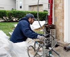 Crew installing push pier on corner of home