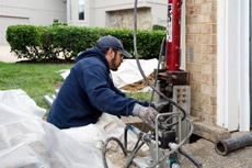Crew installing push pier on corner of home