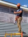OBA and Habitat for Humanity volunteer hammering exterior siding.