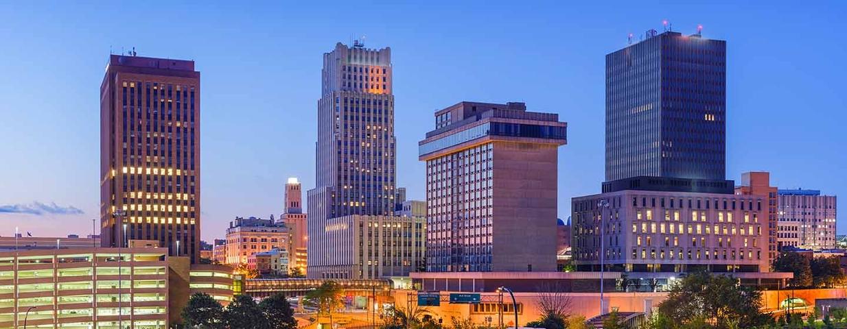 City skyline at dusk with tall buildings and a clear blue sky.