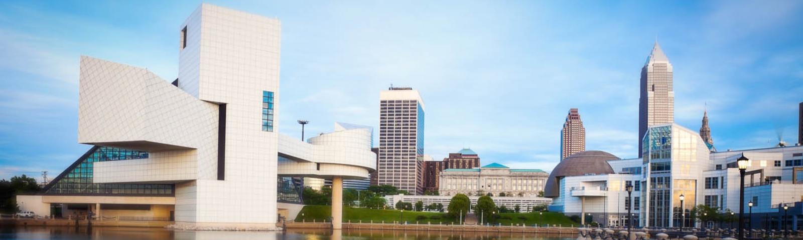 City skyline with modern white building by the waterfront under a blue sky.