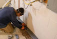 A worker waterproofing a basement.