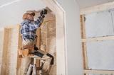 man on ladder uses drill on wall