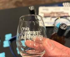 Ohio Basement Authority logo on a souvenir tasting glass from the Cleveland Cheese, Wine, and Chocolate Fest