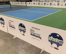 Indoor pickleball court with branding signs for Pickle in the Land and Ohio Basement Authority along the side.