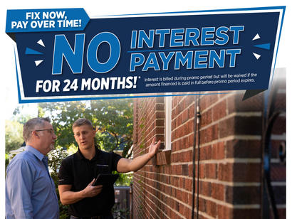 Two men talk outside a brick house under a sign reading "No Interest Payment for 24 Months!